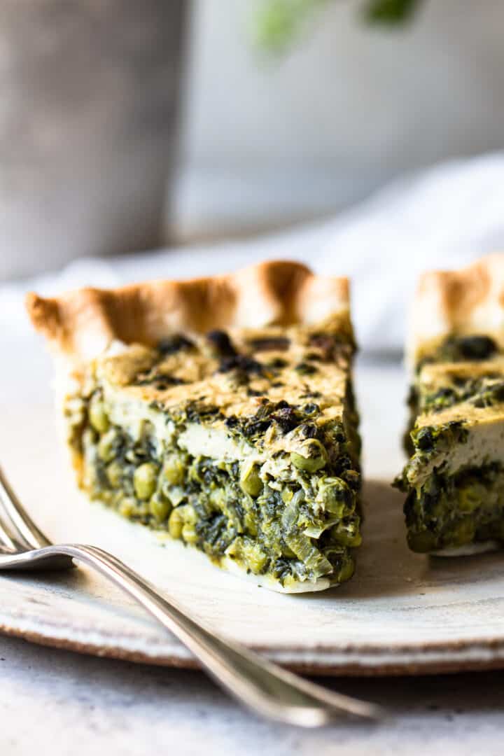 Close-up picture of one slice of spinach quiche with leek and green peas.