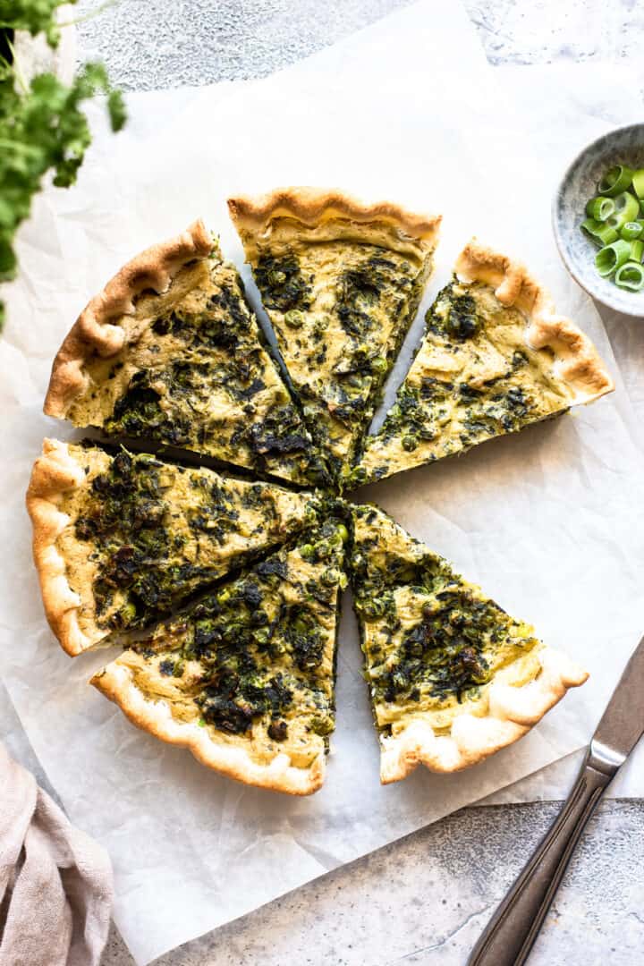 6 slices of spinach quiche arranged in a circle on white parchment paper.