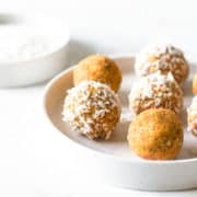 Carrot cake energy balls coated with shredded coconut on a plate.