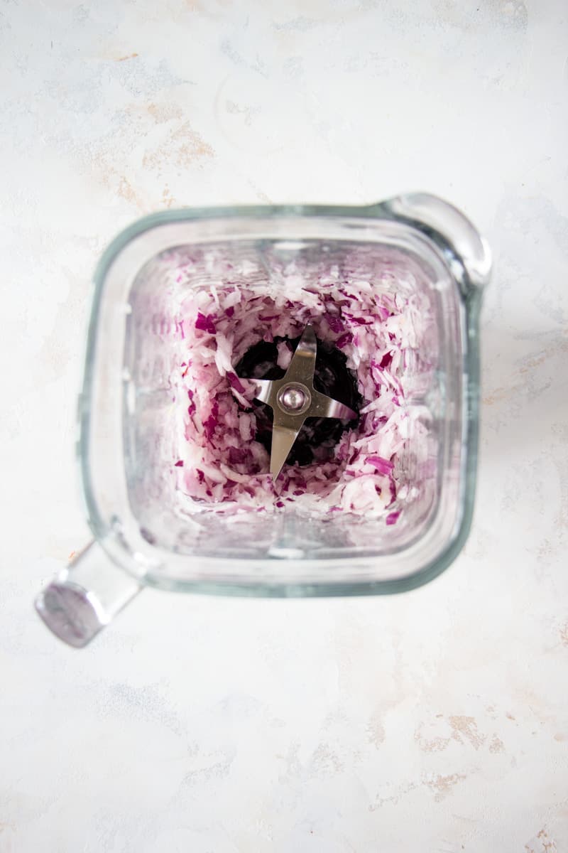 Chopped red onions and shallots in a high-speed blender.