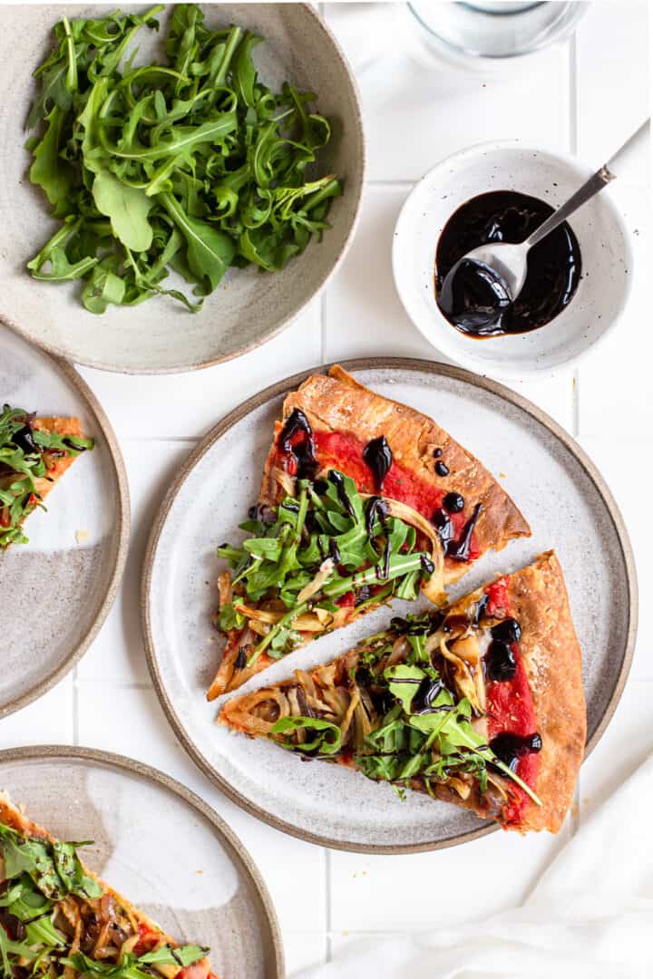 Two slices of cheeseless pizza with fennel on a white and grey ceramic plate.