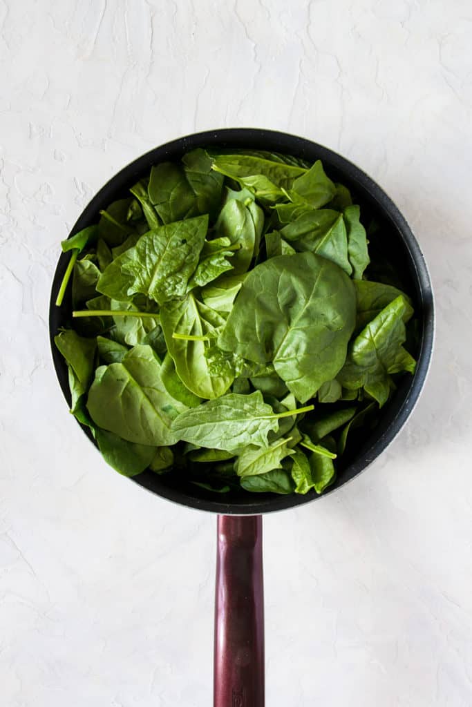 Fresh spinach in a pan for vegan spinach sauce