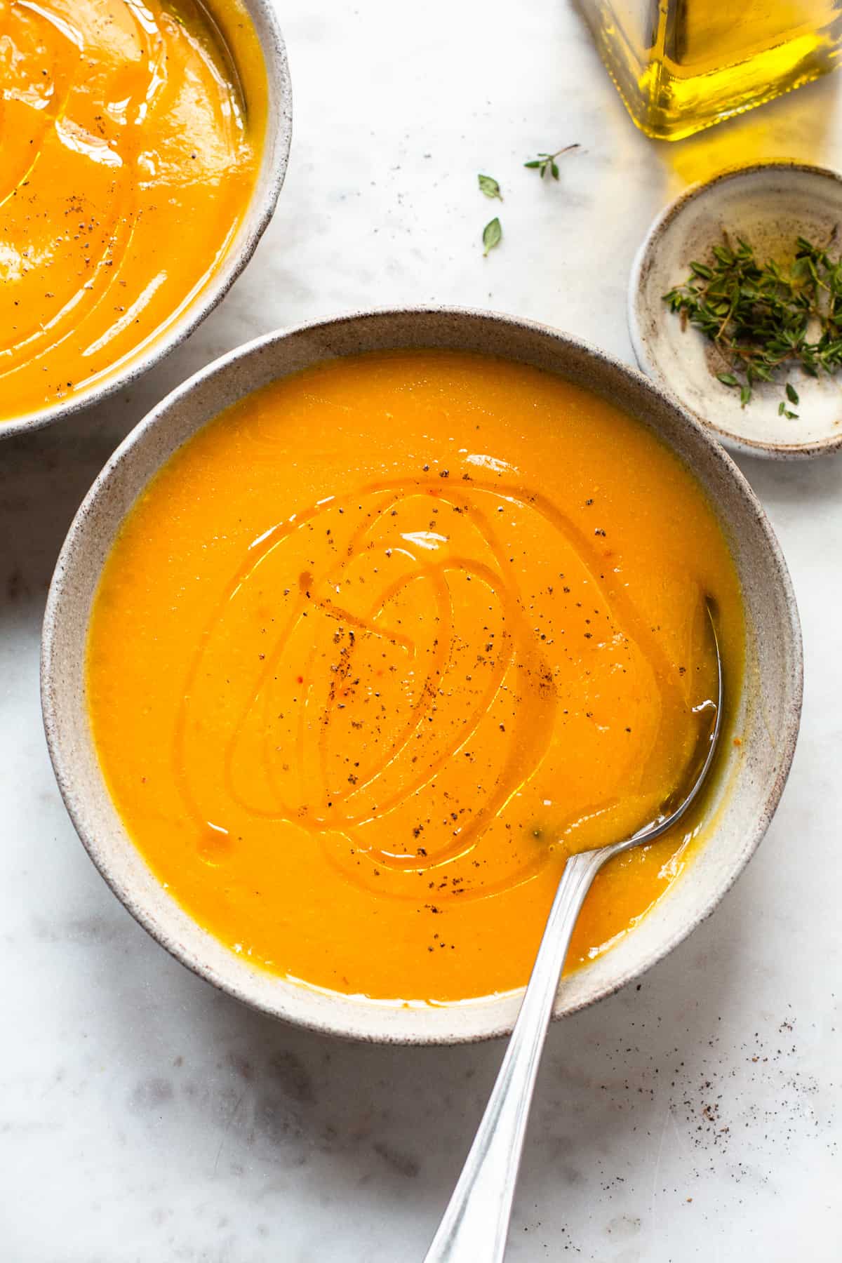 Bright orange soup in a grey ceramic bowl with an antique tablespoon.