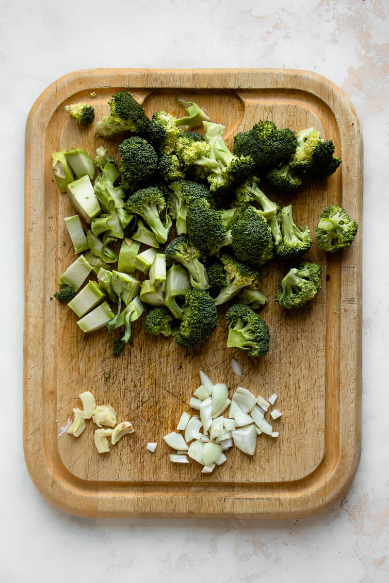 Chopped broccoli, onions and garlic on a cutting board.o