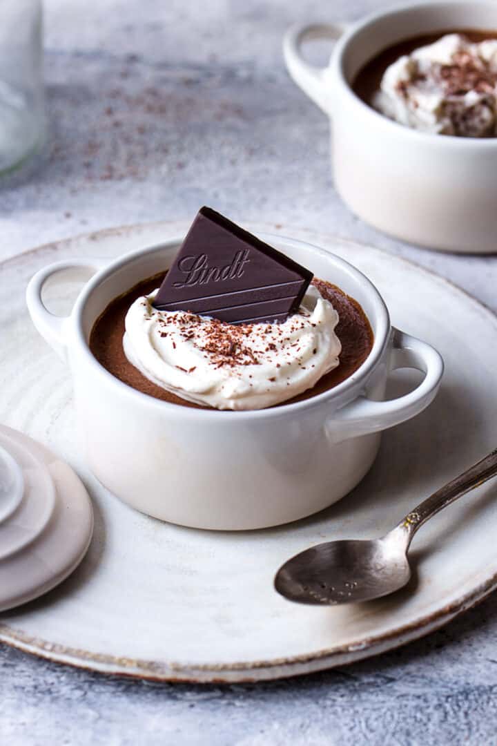Aquafaba chocolate mousse topped with plant-based yogurt and a square of chocolate.