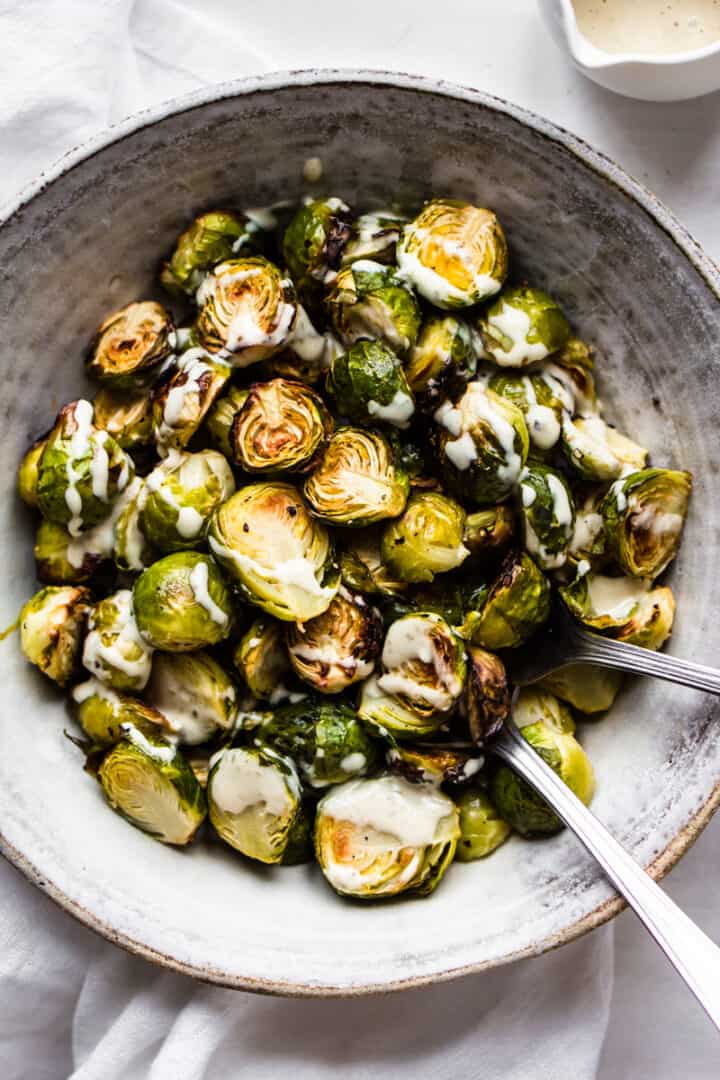Vegan roasted Brussels sprouts with caesar dressing in a bowl.