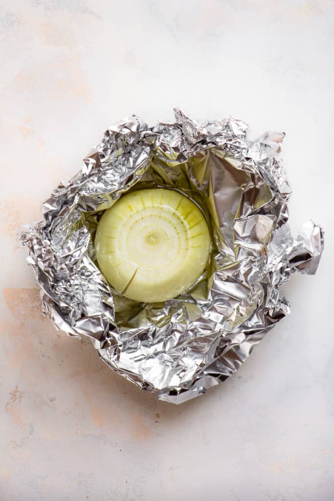 Peeled onion wrapped in aluminum foil.