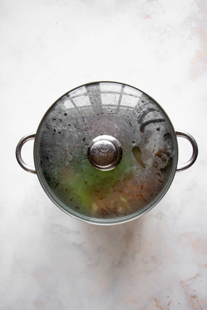 Simmering vegetable broth from scraps with a lid on.