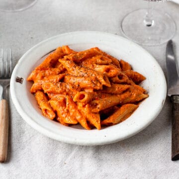 Vegan vodka sauce pasta on a table with a linen tablecloth.