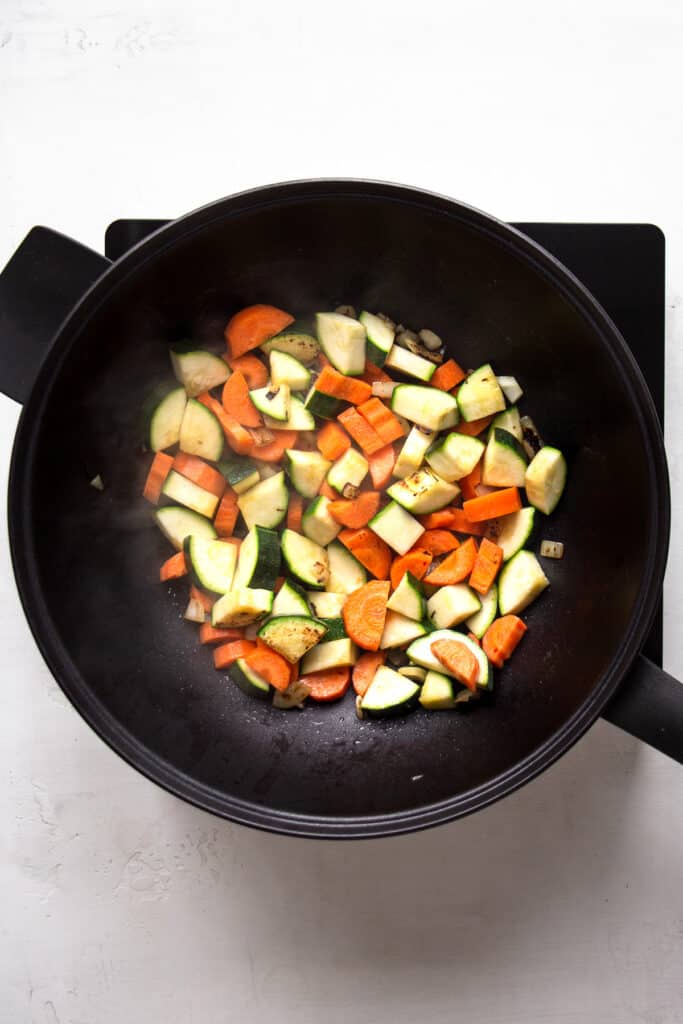 Sauteed vegetables in a large black wok pan.