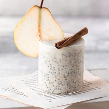 Pear overnight oats in a glass jar with a slice of pear stuck onto the edge.