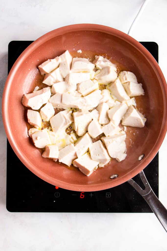 Large silken tofu pieces in a non-stick pan.