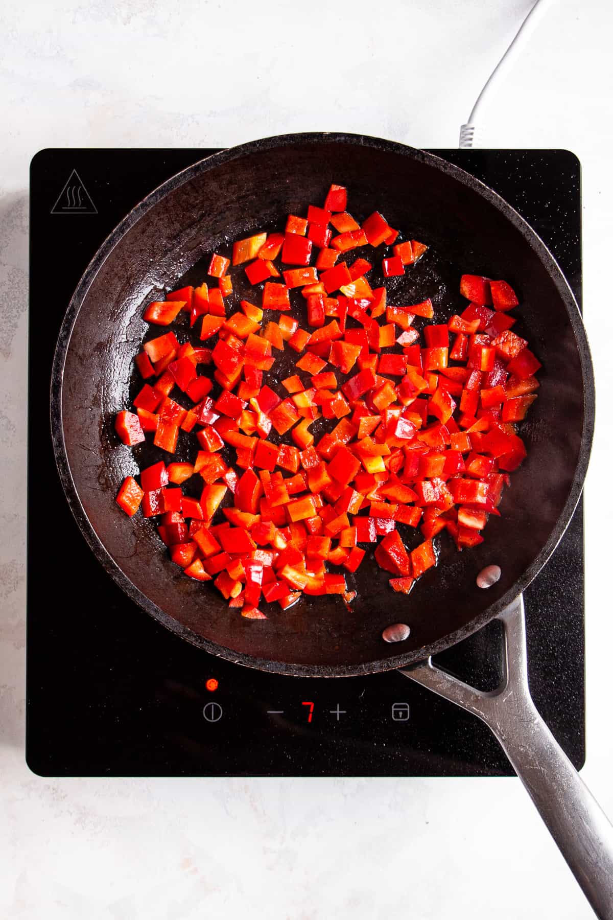 Sautéed red pepper in a black pan.