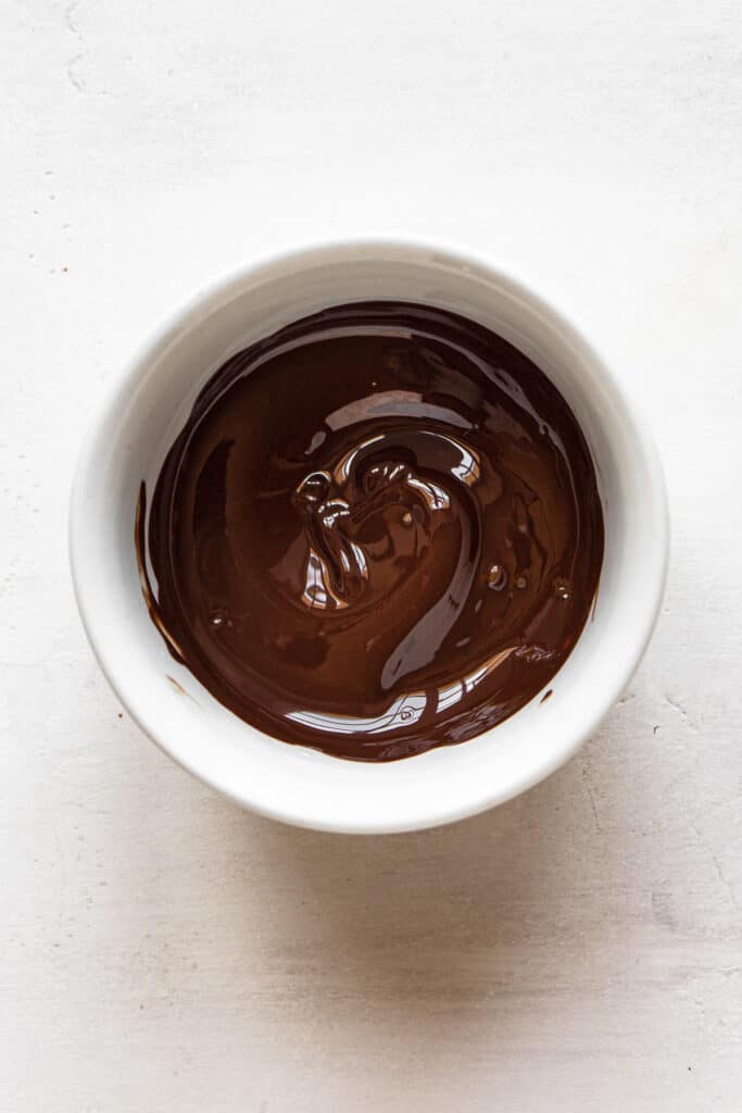 Melted dark chocolate in a small white bowl.
