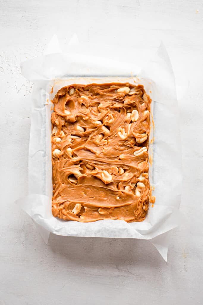 Cashew and peanut butter mixture layered in a small glass baking dish with parchment paper.