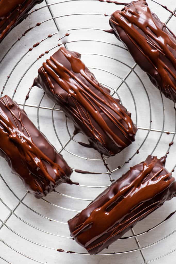 Snickers drizzles with extra chocolate on a cooling rack.