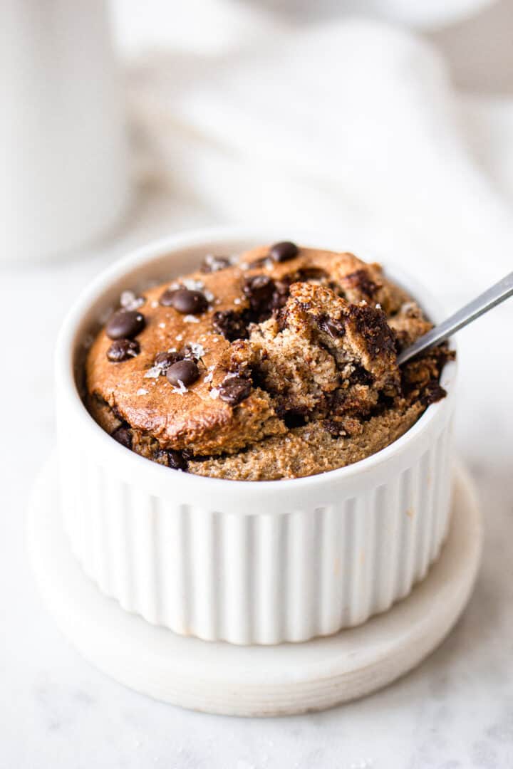 Spoon inserted in a white ramekin with baked oats.
