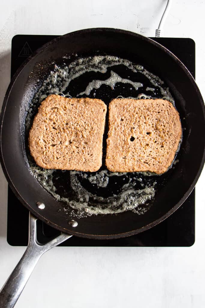 Two slices of soaked french toast mixture in a pan.