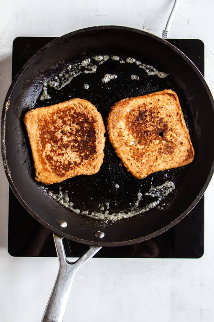 Two slices of caramelized french toast mixture in a pan.