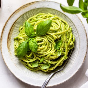 Grey ceramic plate with twisted linguine covered with green basil pesto.