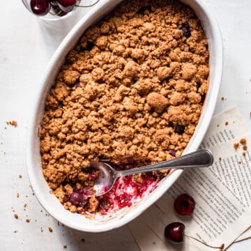 Baked cherry crisp where a spoonful is missing.