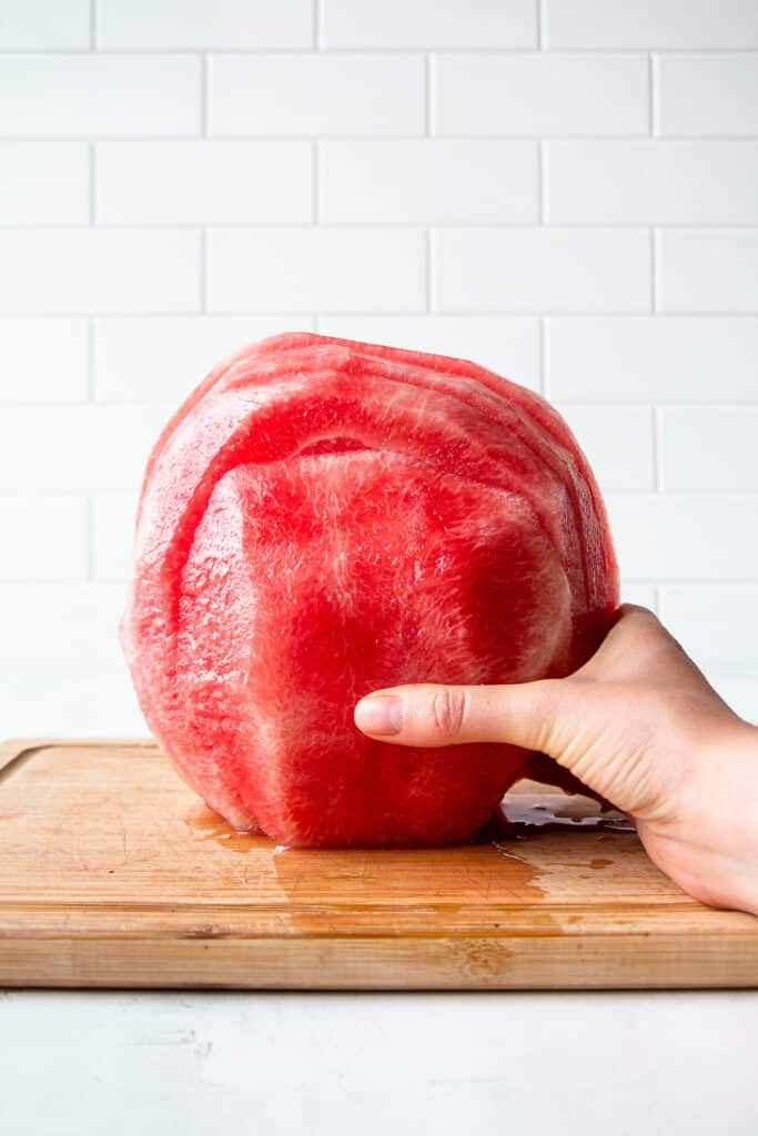 Hand holding a sliced watermelon vertically.