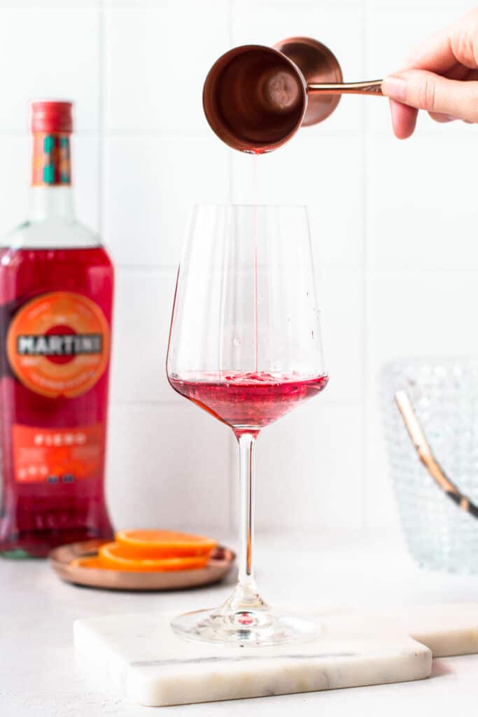 Hand pouring Martini Fiero in a stemmed wine glass.
