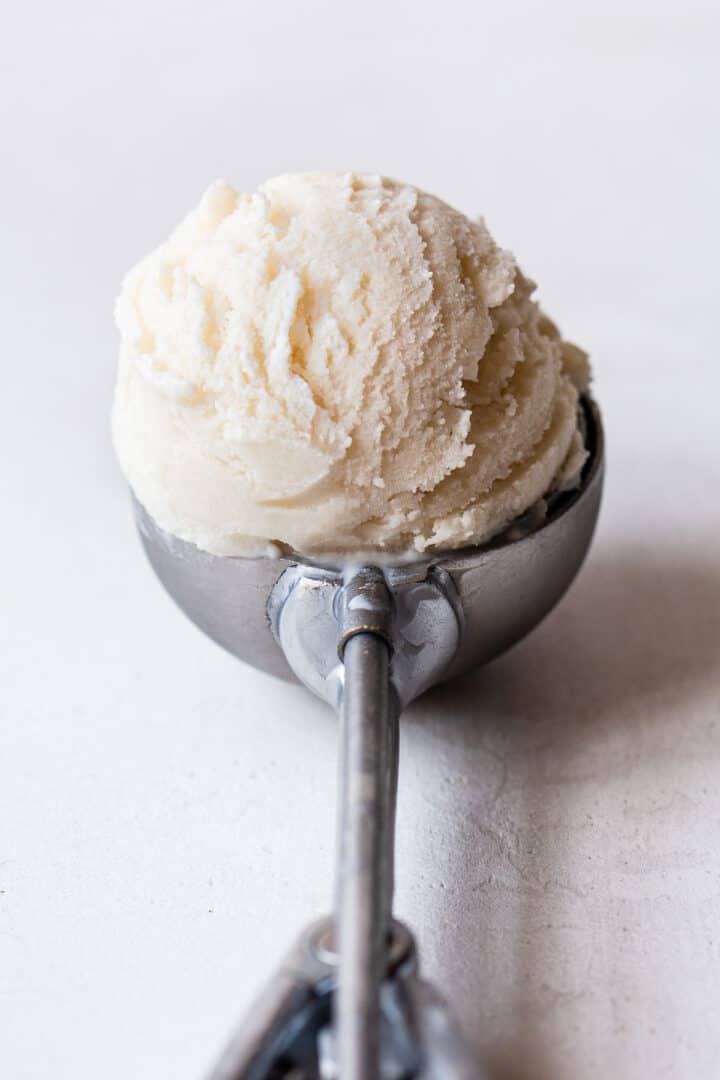 Scoop of frozen yogurt ice cream in a silver ice cream scoop.