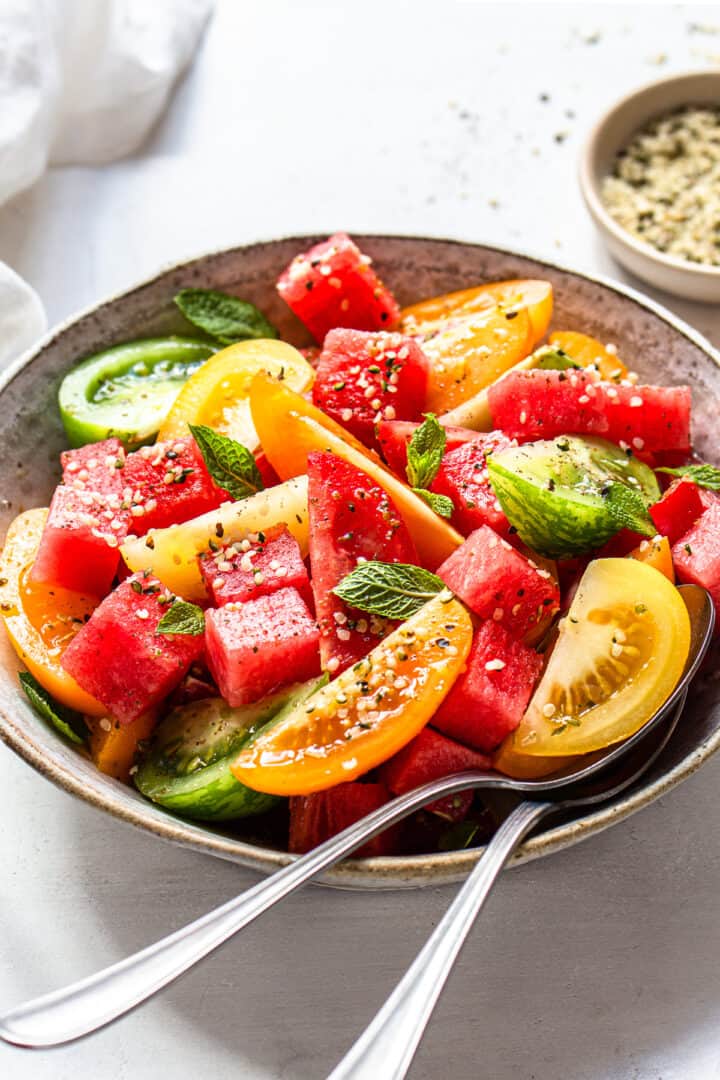 Close-up photo of a tomato and watermelon salad with fresh mint.