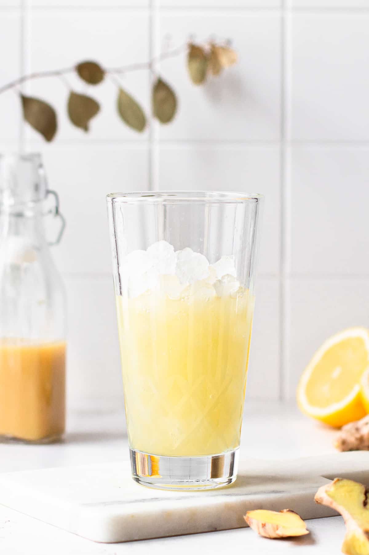 Glass cocktail shaker filled with ice and yellow liquid.