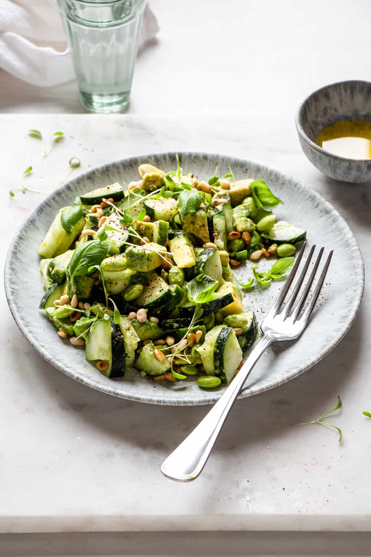 Close-up photos of a cucumber and avocado salad with an antique fork.