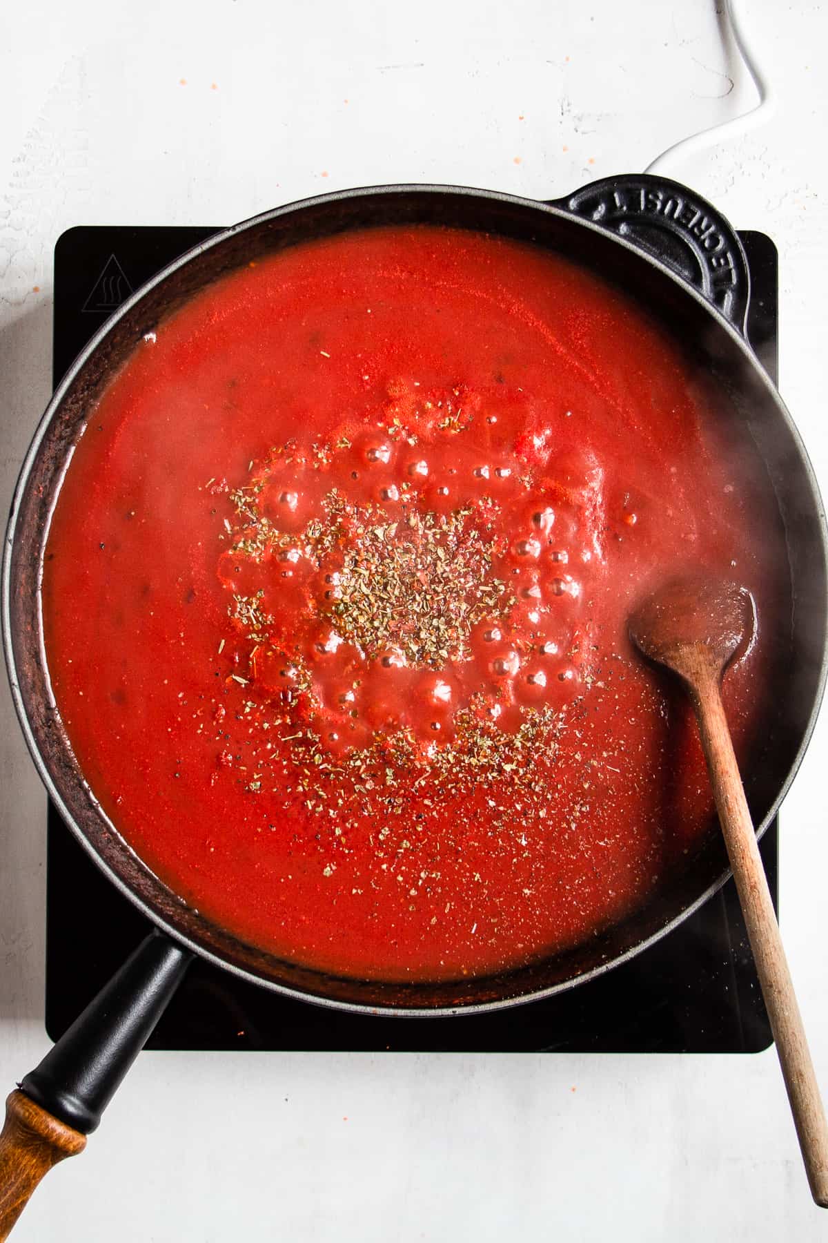 Simmering passata tomato sauce in a black pan.