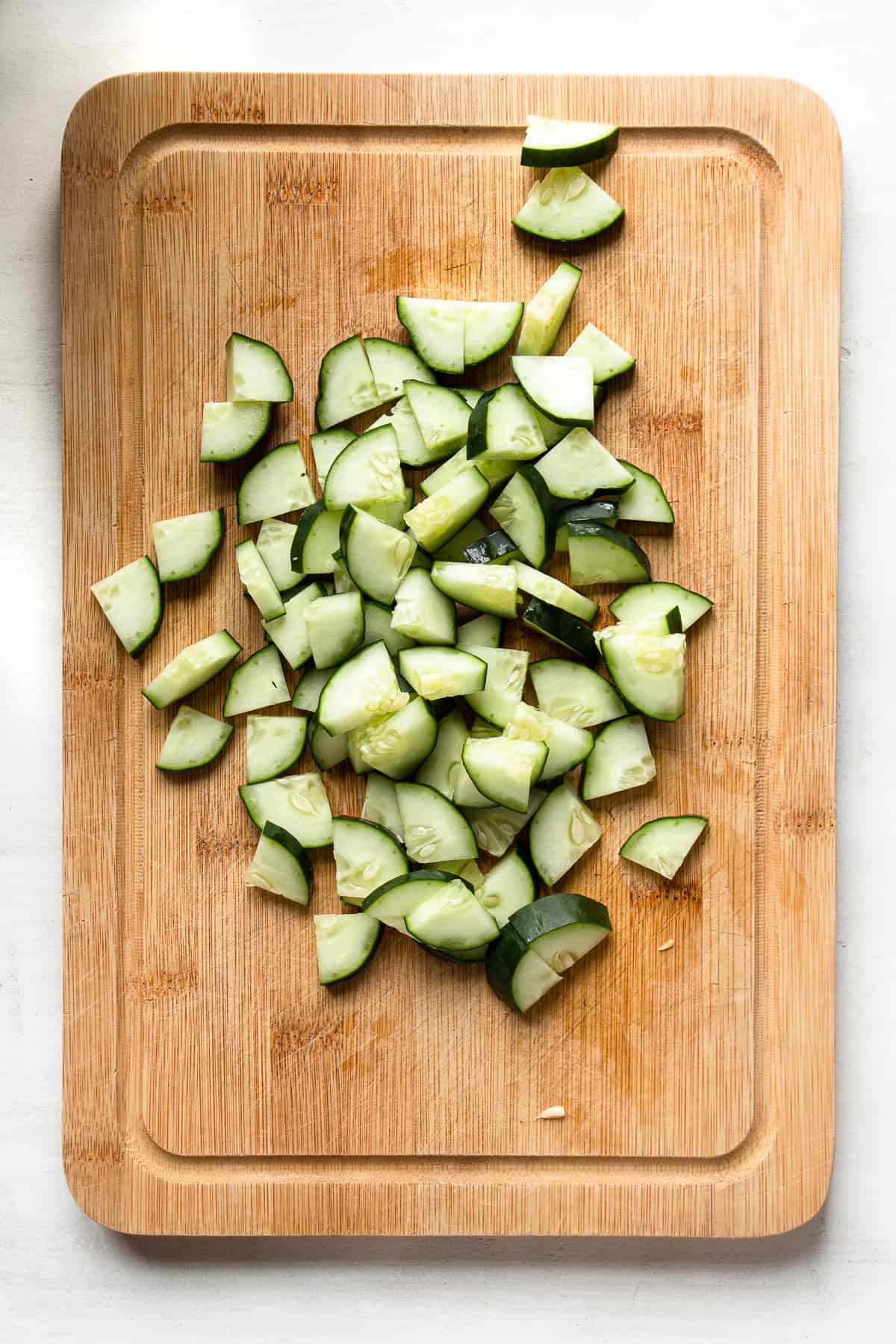 Sliced English cucumber on a wooden board.