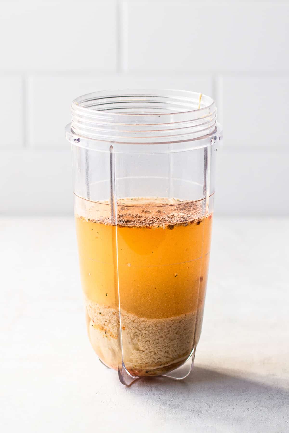 Vegetable broth, cashew butter and nutritional yeast in a small blender container.