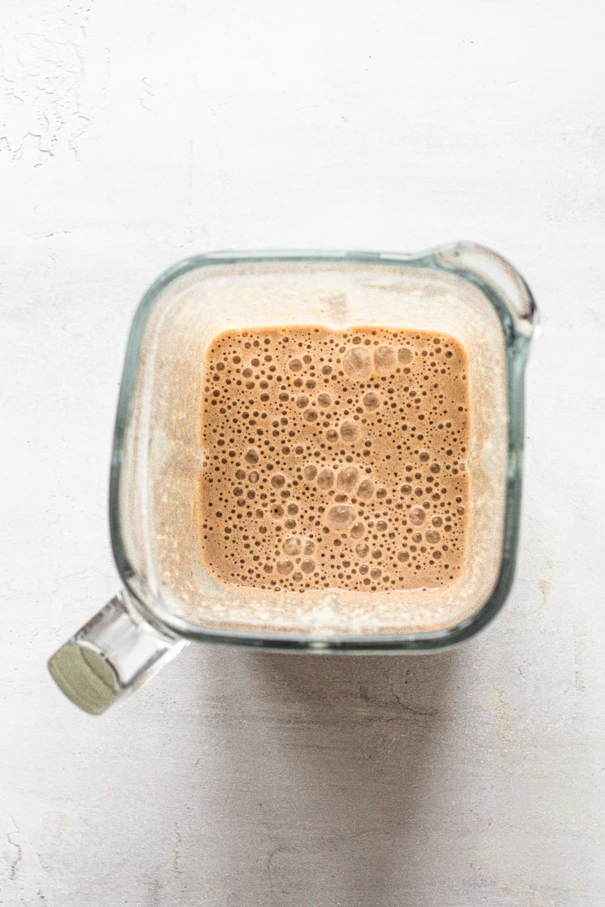 Blended banana peanut butter smoothie in a blender.