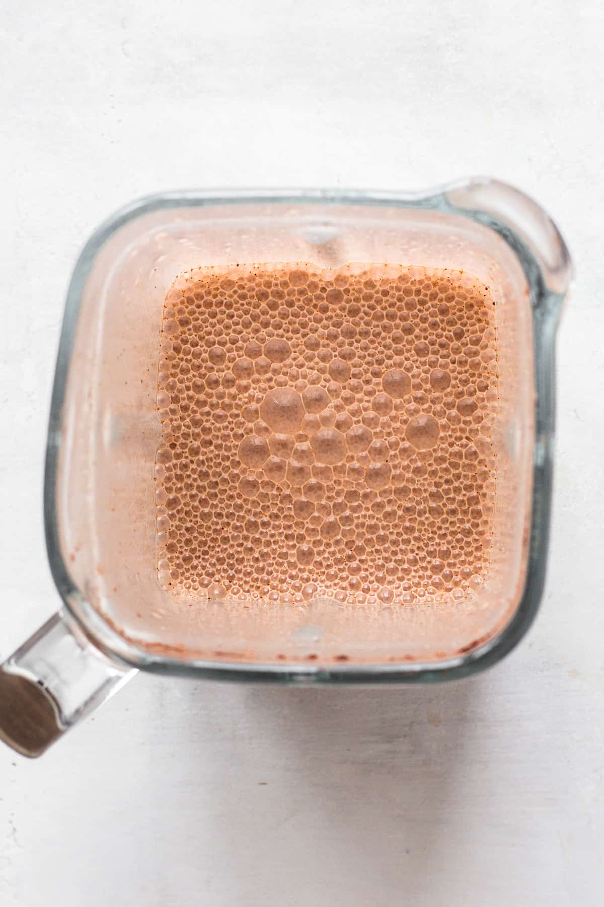 Top view of a blended chocolate smoothie with lots of small air bubbles.