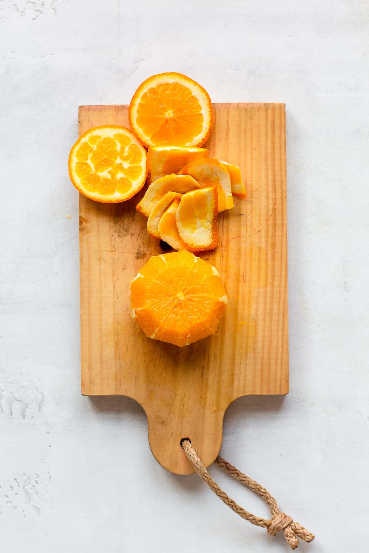Peeled orange and its peels on a small wooden cutting board.