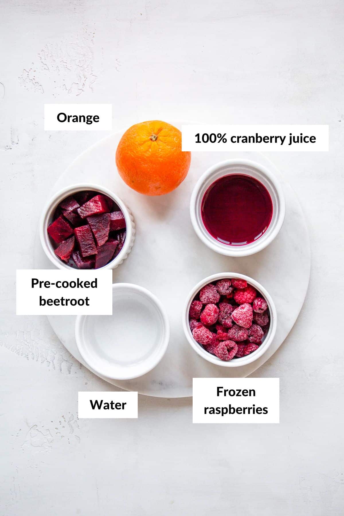 Ingredients for cranberry juice smoothie in white ceramic bowls with descriptive labels.