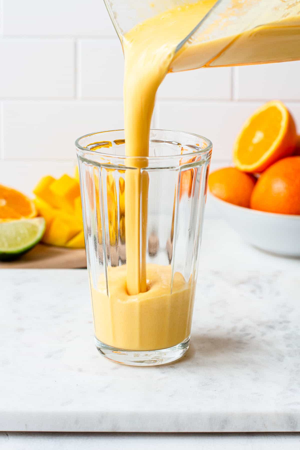 Orange smoothie poured into a ribbed glass.