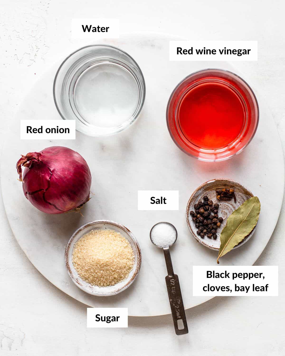 Ingredients for red wine vinegar pickled onions in small jars with descriptive labels.