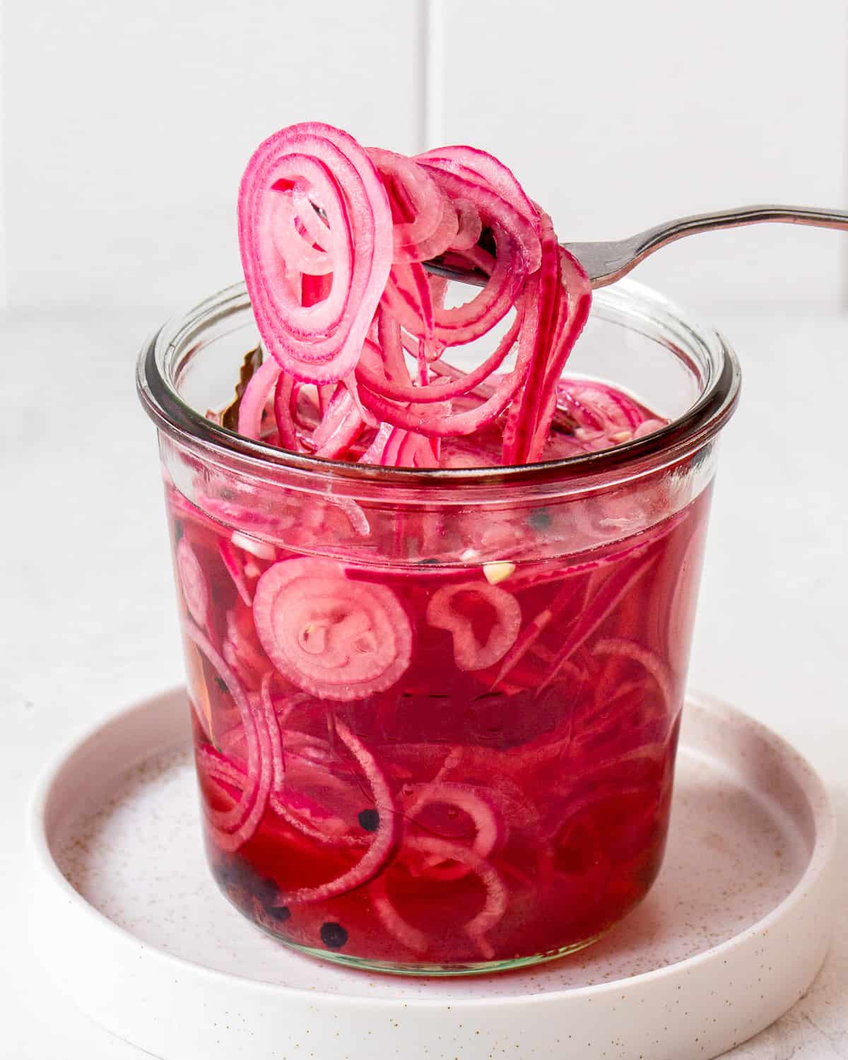 Fork with vinegar pickled red onion slices.
