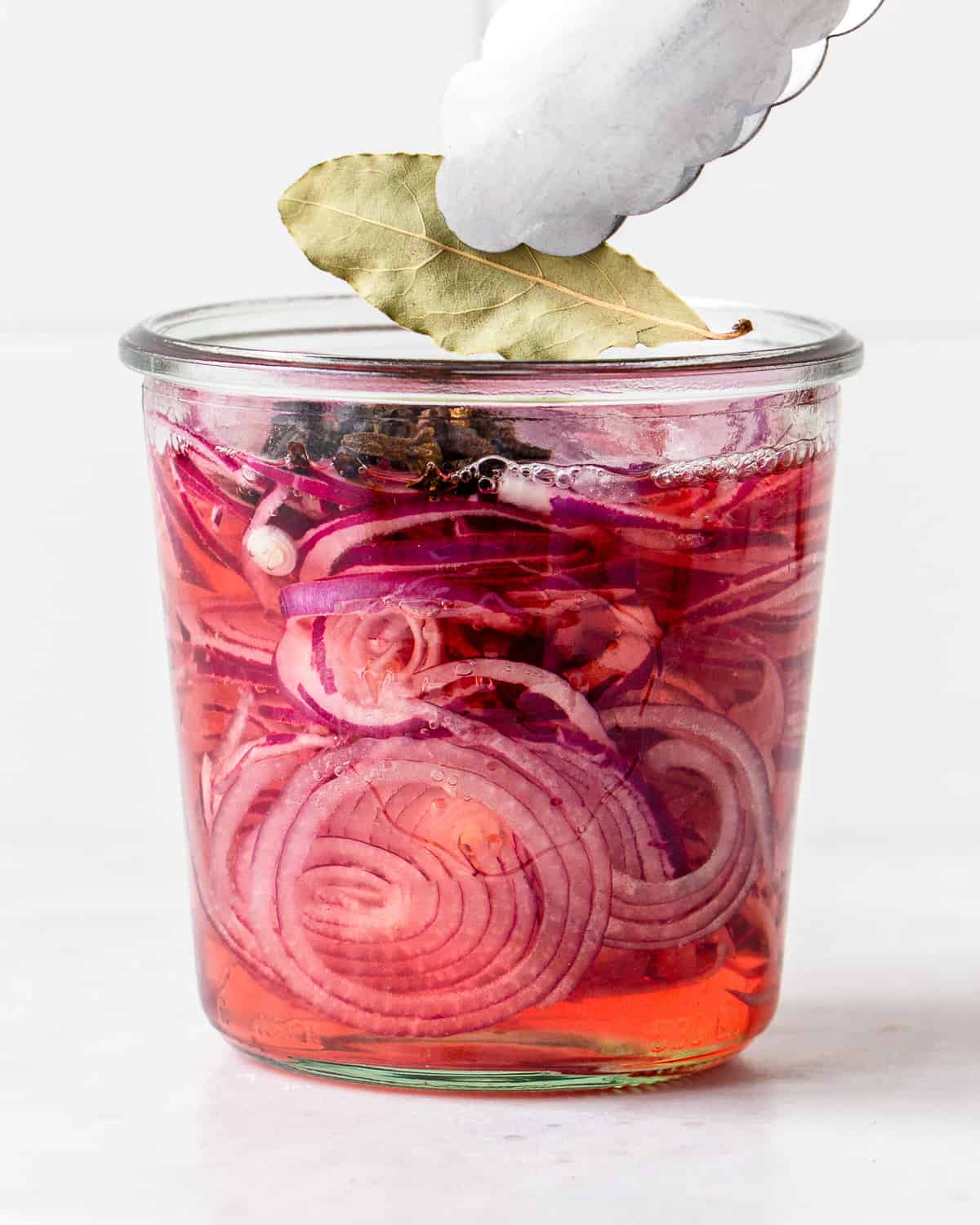 Sliced red onions in vinegar brine with black pepper, cloves and a bay leaf.