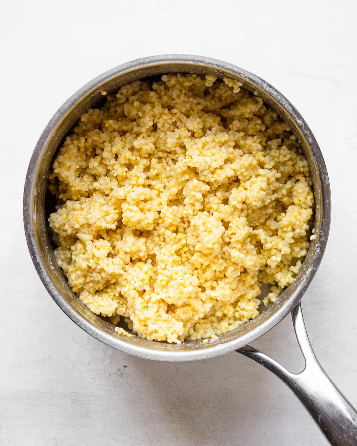 Cooked and fluffed millet in a small pot.