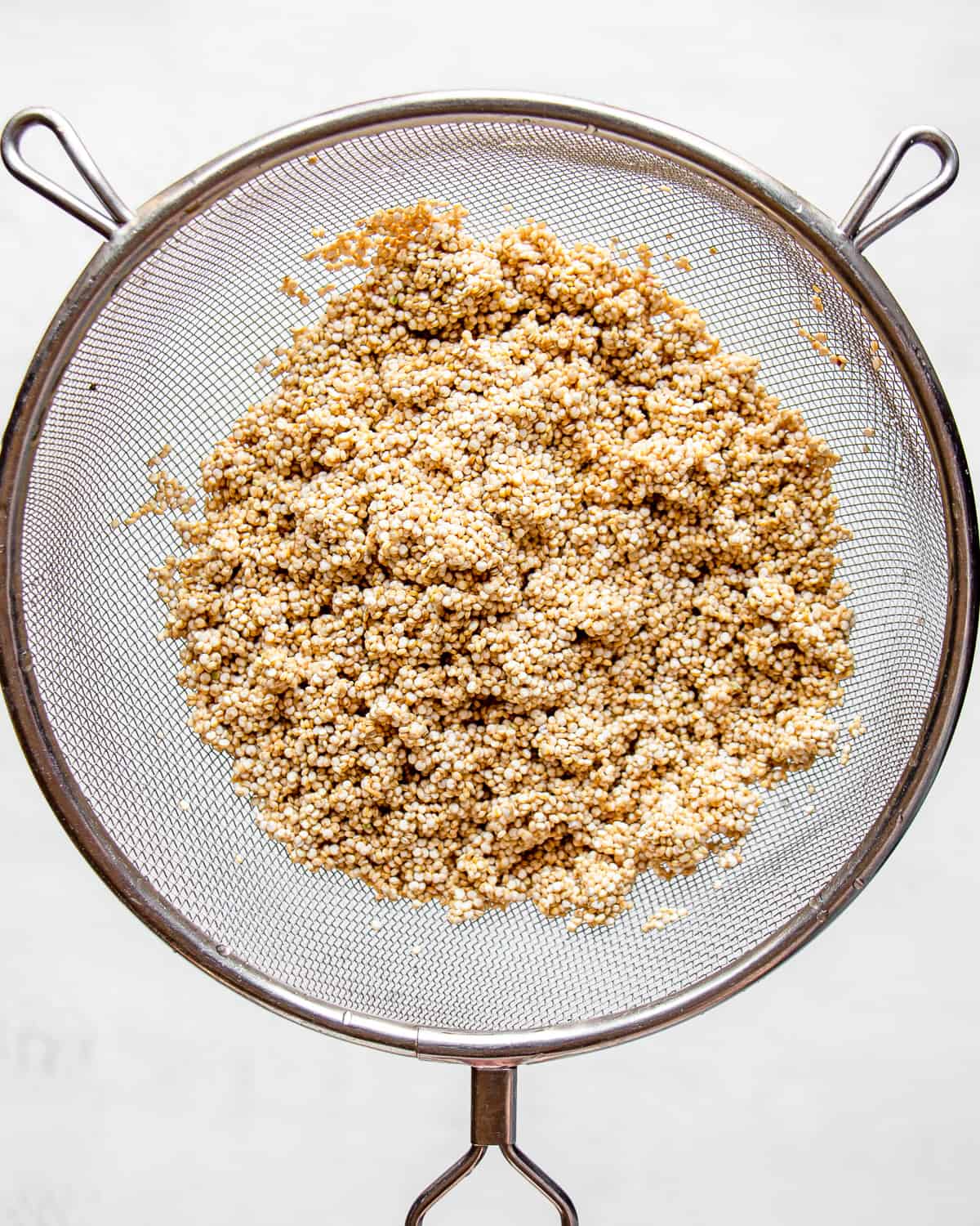 Rinsed white quinoa in a fine-mesh sieve.