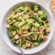 Raw broccoli salad with smoked tofu and edamame beans in a deep white plate.