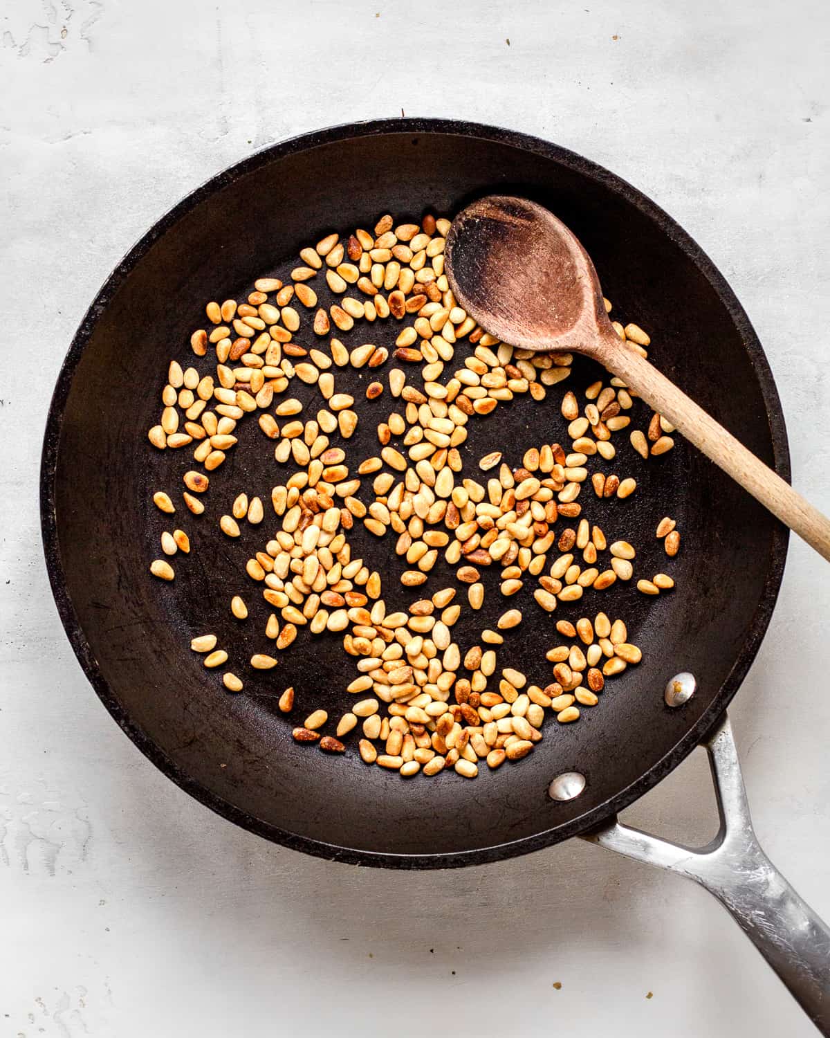 Roasted pine nuts in a cast-iron pan.
