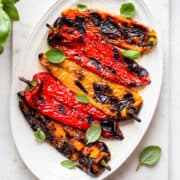Grilled sweet peppers with salt and small basil leaves.