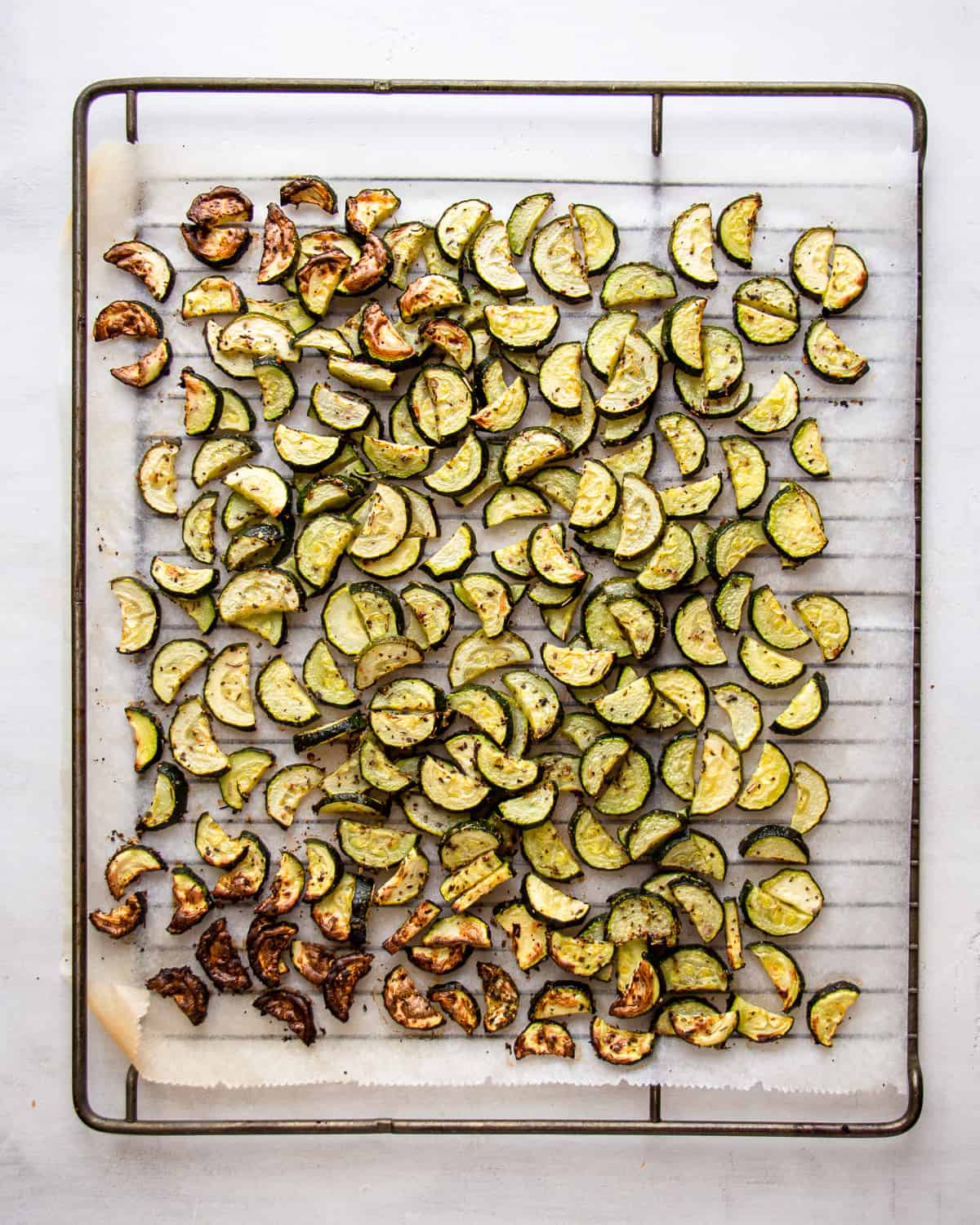 Oven-roasted zucchini on a parchment linked baking tray.