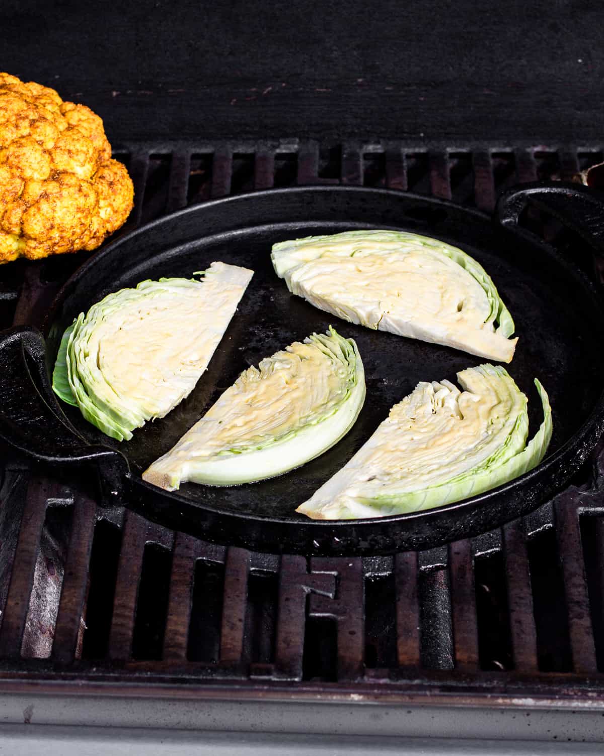 Cabbage wedges on the griddle of a gas grill.