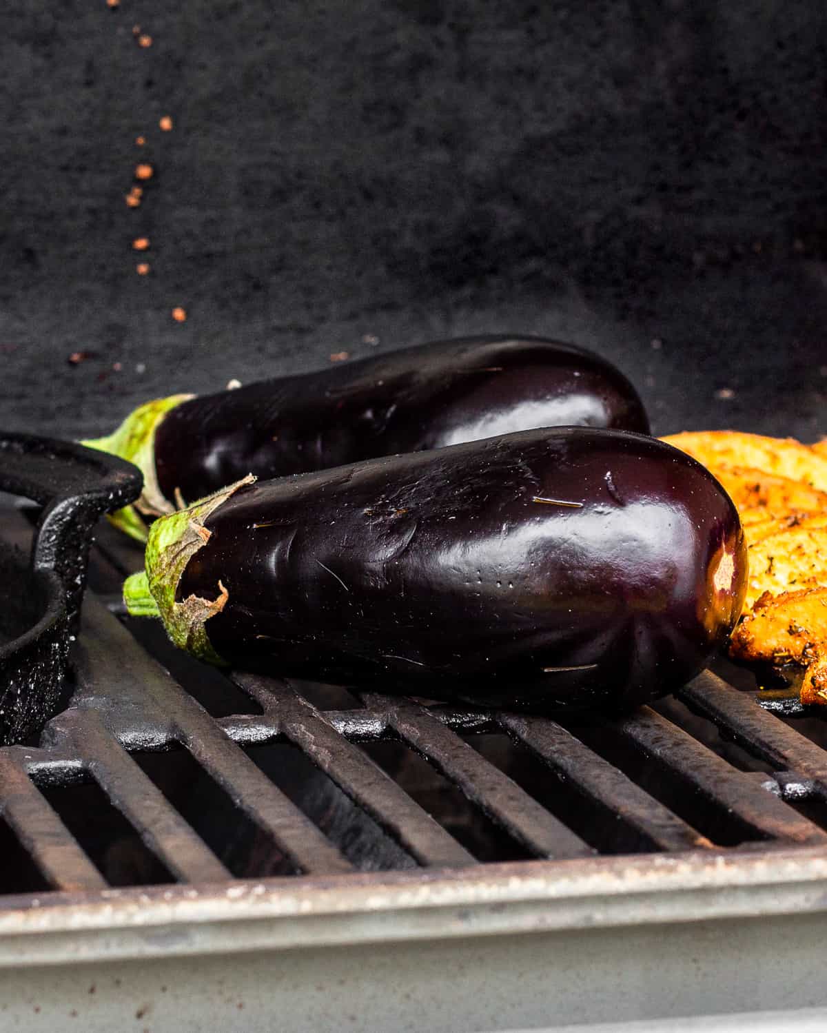 Two whole eggplants on a gas grill.